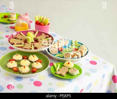 Platten von Fingerfood auf Tisch einschließlich Thunfisch Sandwiches, Käse, Gebäck, Sandwiches und Gurken sticks Stockfoto