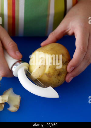 Das Mädchen Hände peeling Kartoffel mit Schäler, close-up Stockfoto
