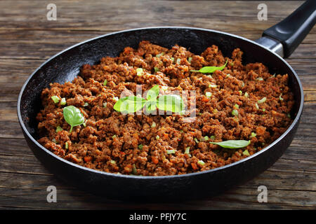 Hot Juicy Rinderhackfleisch geschmort mit Tomatensauce, Gewürze, Basilikum, fein gehackt Gemüse und Sellerie in der Pfanne, klassisches Rezept, Seitenansicht von abov Stockfoto