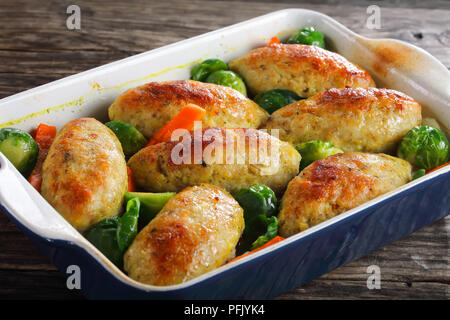 Köstliche Fischgerichte Schnitzel gebacken in einem Backofen mit Karotten, Zwiebeln, Rosenkohl, in Auflaufform, Ansicht von oben, close-up Stockfoto