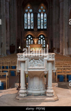 Grossbritannien, England, Hampshire, Romsey, Romsey Abbey, Blick auf das Taufbecken mit Altar und Buntglasfenstern im Hintergrund Stockfoto