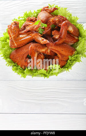 Köstlich knusprige smoked Chicken Wings auf einem Salat Salat auf einem weißen Teller auf Küche aus Holz Tisch serviert, vertikale Ansicht von oben Stockfoto
