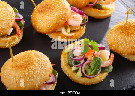 Leckere kleine Burger oder pinchos mit Garnelen, Tintenfisch, Muscheln, roten Zwiebeln, Spinat und gehackten Gurken, Spanien Küche, close-up Stockfoto