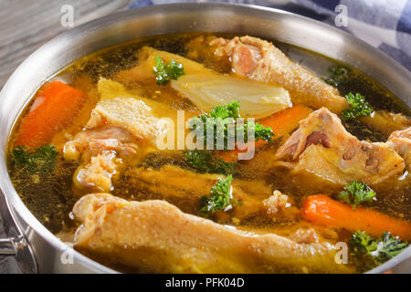 Der leckere Hühnerbrühe mit Stücken von Hahn Fleisch am Knochen und Gemüse in eine Kasserolle, schließen, Ansicht von oben Stockfoto