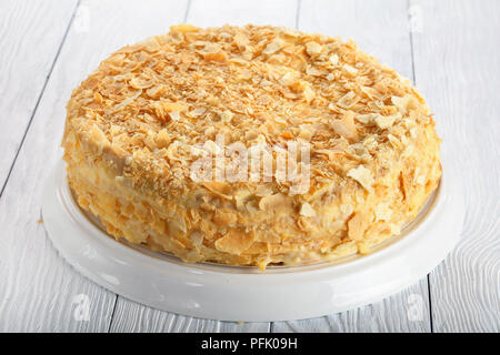 In der Nähe von köstlichen hausgemachten Kuchen Blätterteig Napoleon mit Vanillesauce Creme auf weißen Teller auf Holztisch geschichtet, Ansicht von oben Stockfoto