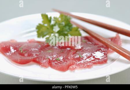 Sushi serviert mit Petersilie auf Teller mit Stäbchen Stockfoto