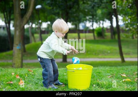 Blonde Junge im Park werfen Müll in Fach Stockfoto