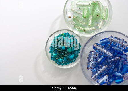 Drei Glasschüsseln mit Grün, Türkis und Blau farbigen Perlen gefüllt, von oben betrachten Stockfoto