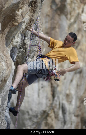 Junger Mann, Klettern, Felswand, rechalking seine Hand Stockfoto