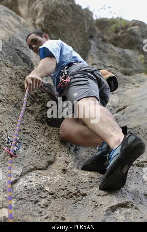 Junge Mann in kurzen Hosen Klettern, halten auf Seil Stockfoto