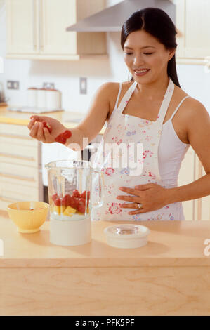 Die Frau in der Küche hinzufügen Früchte zu Blender Stockfoto