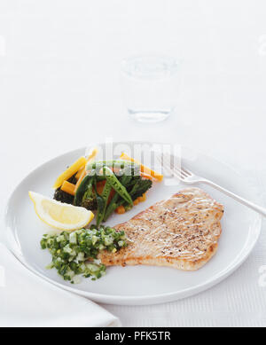 Türkei Schnitzel mit gedünstetem Gemüse und Salsa, auf einer Platte und einem Glas Wasser Stockfoto