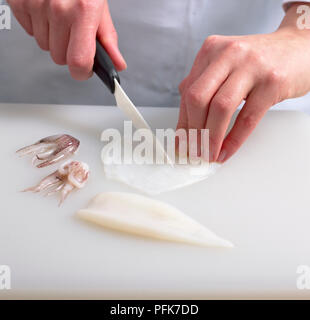 Hände, die Messer schneiden squid in Streifen, Tentakeln in der Nähe, close-up Stockfoto