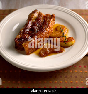 Schweinebraten Bauch und Apfelscheiben auf Platte, close-up Stockfoto