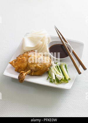 Knusprig gebratene Entenkeule, serviert mit chinesischen Pfannkuchen, Frühlingszwiebeln und Gurken und Schüssel von hoisin Sauce, Essstäbchen, close-up Stockfoto