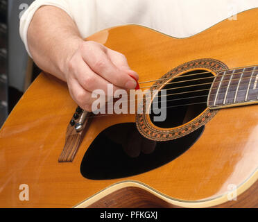 Des Menschen Hand spielen akustische Gitarre mit Guitar Pick, close-up Stockfoto