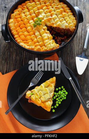 Unglaublich lecker Shepherd pie oder Cottage potato Lamm Kuchen in backform und ein Teil auf der Platte auf Holztisch, authentische Rezept des englischen Cuis Stockfoto