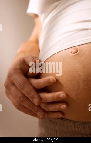 Frau und die Hände des Mannes auf die Frau schwanger Bauch, close-up Stockfoto