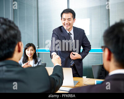 Zwei asiatische Geschäftsleute Händeschütteln über Tisch vor der Verhandlung. Stockfoto