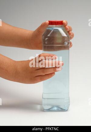 Child's Hände halten transparente Kunststoff Trinkflasche Stockfoto