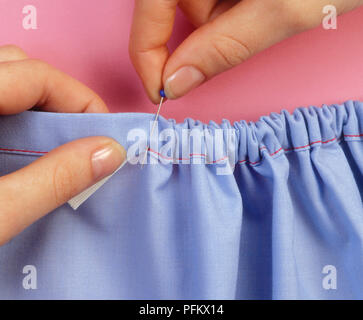 Mit Fingern elastisch durch Gehäuse Saum an jeder Öffnung und stopfte das Ende innen Saum Spannbetttuch zu Stift Stockfoto