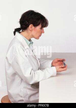 Weibliche Labortechniker Prüfung der Probe, Seitenansicht Stockfoto