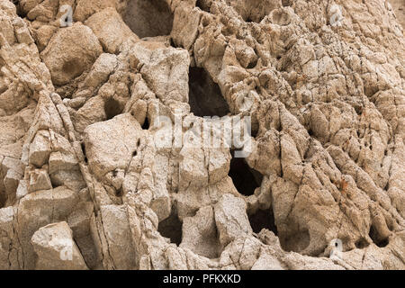 Nahaufnahme des Desert Rock Wall mit tiefe dunkle Löcher und Risse auf der Oberfläche, horizontales Format Stockfoto