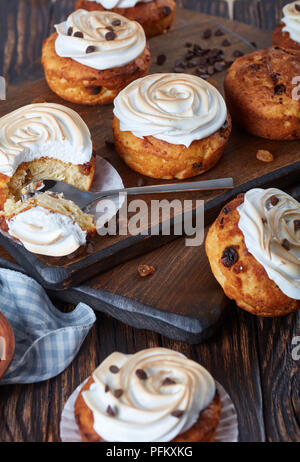 Frisch gebackene hausgemachte Muffins mit Schokolade Tropfen und Rosinen mit schönen meringue Rosen dekoriert, Ansicht von oben, close-up Stockfoto