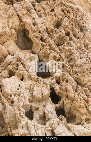 Nahaufnahme des Desert Rock Wall mit tiefe dunkle Löcher und Risse auf der Oberfläche, Hochformat Stockfoto