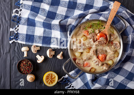 Blanquette de veau-Stücke von Kalbfleisch, Pilze, Pearl, Zwiebeln, Kräutern, Gemüse mit cremigen Soße in einer Kasserolle mit Küchentuch, Pfefferkörner und Bu Stockfoto