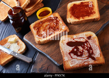 Aussie herzhaften Toast zum Frühstück mit Butter und Vegemite - eine dicke Australische gesunde Lebensmittel verbreiten von übrig gebliebenen Brauereien Hefe mit Gemüse extrahieren Stockfoto