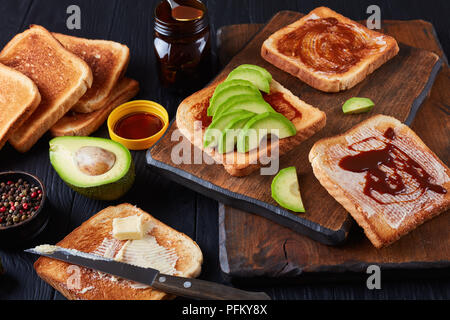 Pikanter Toast mit Butter, Avocado-, Scheiben und gesunde Lebensmittel verbreiten von übrig gebliebenen Brauereien Hefe mit Gemüse und Gewürze Extrakt, Ansicht von oben, Stockfoto