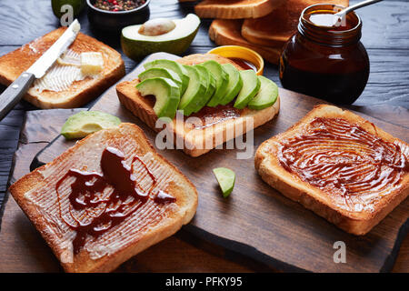 Pikante gesunde Toast mit Butter, Avocado-, Schichten und verbreitete sich von übrig gebliebenen Brauereien Hefe mit Gemüse und Gewürze Extrakt, Ansicht von oben, Clos Stockfoto