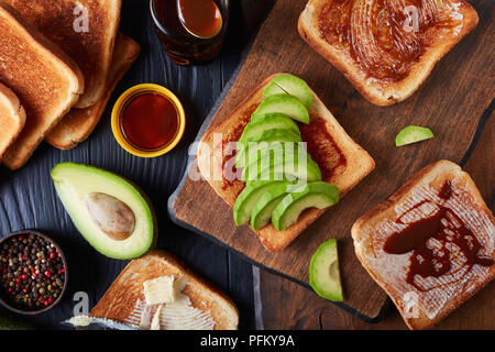 Pikante gesunde Toast mit Butter, Avocado-, Schichten und verbreitete sich von übrig gebliebenen Brauereien Hefe mit Gemüse und Gewürze Extrakt, Ansicht von oben, Clos Stockfoto