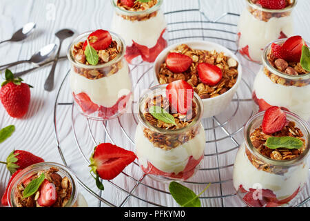 In der Nähe von köstlichen hausgemachten Müsli mit frischem Joghurt und reife Erdbeeren in Teil Gläser Metallgitter geschichtet, horizontale Ansicht von oben Stockfoto