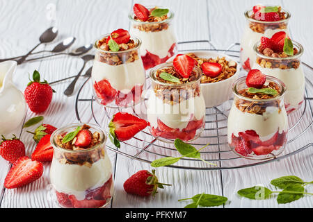 Köstliches hausgemachtes Müsli mit frischem Joghurt und reife Erdbeeren in Teil Gläser Metallgitter, horizontale Ansicht von oben, close-up Stockfoto