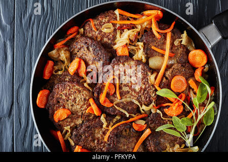 Leber Pfannkuchen geschmort mit Karotte und Zwiebel in einer Pfanne, Ansicht von oben, flach, close-up Stockfoto