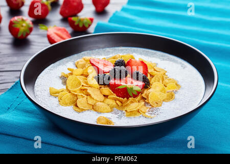 Super Essen - ein Teil von Chia Samen mit Milch und Cornflakes garniert mit frischen Erdbeeren, und Maulbeeren in einer Schüssel auf schwarzem Holz- Tabl Stockfoto