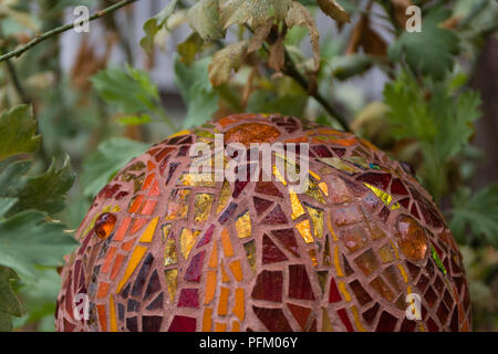 Nahaufnahme von Mosaik garten Kugel in den Farben Orange, Rot und Gold aus buntem Glas Fliesen, abstrakte Design Stockfoto