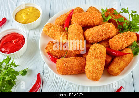 Spanisch frittierte golden braun Kroketten, croquetas auf einem weißen Teller mit Paprika, Senf und Tomatensauce auf einen hölzernen Tisch, Blick her Stockfoto