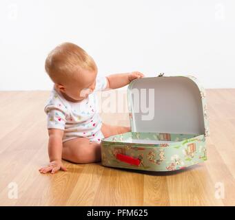 Baby Mädchen sitzen auf dem Boden öffnen Koffer Stockfoto