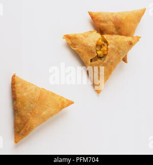 Drei Samosas, leicht eingerissen, pflanzliche Füllung. Stockfoto