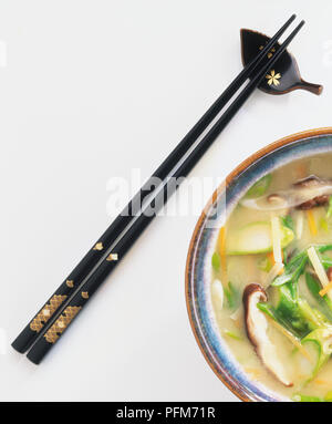 Reich verzierte schwarze Essstäbchen und Rand der Schüssel mit Suppe im asiatischen Stil. Stockfoto