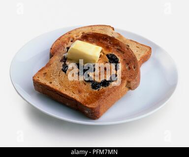 Zwei Scheiben Toast Rosinenbrot mit einem Knopf der schmelzende Butter auf der Oberseite Stockfoto