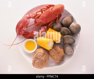 New England Clam backen, ein Teller gekochte Hummer und Muscheln mit Maiskolben serviert, gebackene Kartoffeln und Schüssel von geschmolzener Butter, Ansicht von oben Stockfoto
