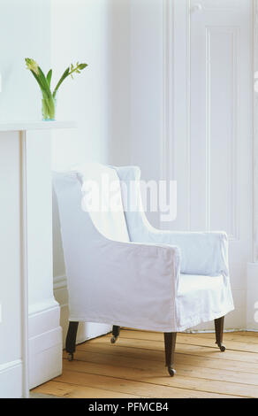 Weiß Sessel mit Rädern hölzernen Beinen in der Ecke des weißen Zimmer mit Holzfußböden, Seitenansicht Stockfoto