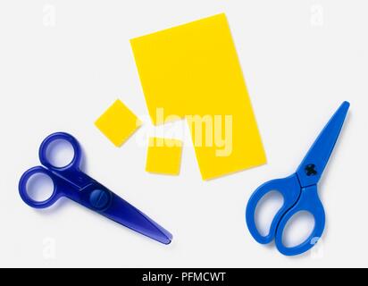 Kunststoff blau Schere und gelbe Karte mit zwei quadratische Stücke schneiden Stockfoto