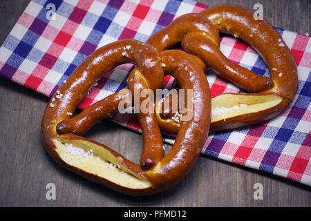 Zwei Brezeln mit checker Tuch auf Holz Tisch Hintergrund. Stockfoto