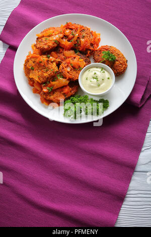 Lecker couscous Fischfrikadellen mit Zwiebel, Möhren und Tomaten auf Platte mit Sauce serviert, im marokkanischen Stil, vertikale Ansicht von oben Stockfoto