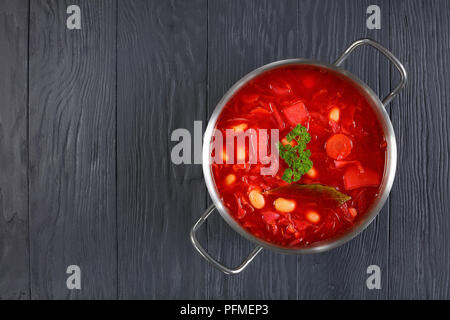 Klassische rote Beete rote Suppe oder Borschtsch in Edelstahl Kasserolle Pfanne auf schwarzen Holztisch, Ansicht von oben Stockfoto